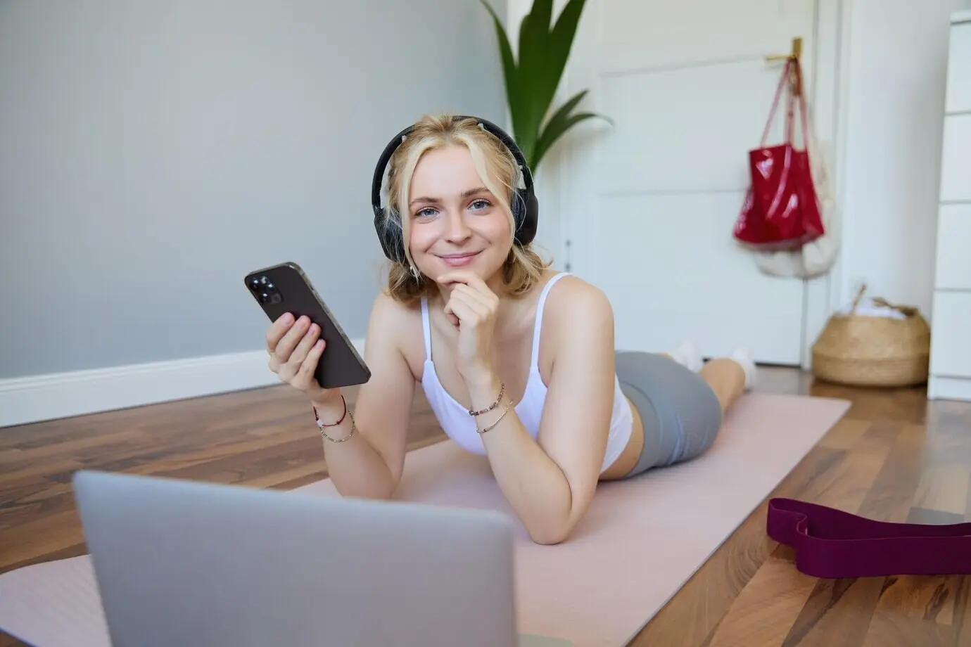 Portrait of a young athletic woman connecting to an online workout session, doing exercises while lying down.